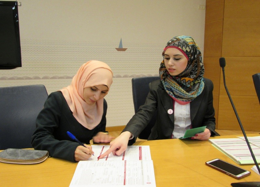 A photograph of a woman filling out paperwork with the help of another woman